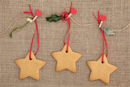 simsearch:400-07614271,k - Christmas gingerbread cookies hanging on a line with red heart pegs, holly, mistletoe and pine leaf sprigs over hessian backgorund. Foto de stock - Royalty-Free Super Valor e Assinatura, Número: 400-07087020