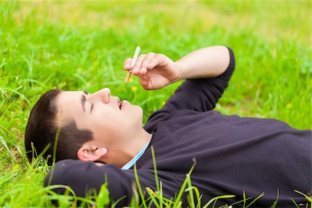 Boy with a cigarette lying in a meadow Stock Photo - Budget Royalty-Free & Subscription, Code: 400-07087064