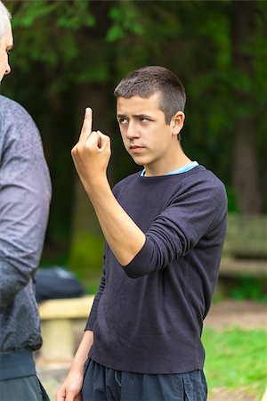 Boy showing middle finger to adult Foto de stock - Royalty-Free Super Valor e Assinatura, Número: 400-07087065