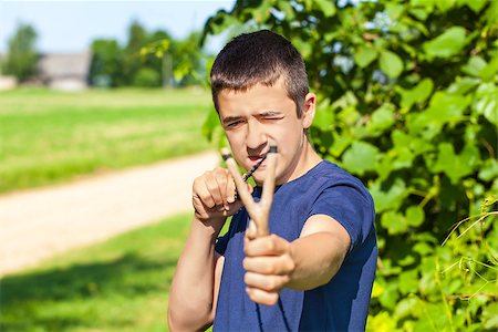Boy with a slingshot at outdoors in summer Foto de stock - Royalty-Free Super Valor e Assinatura, Número: 400-07087072