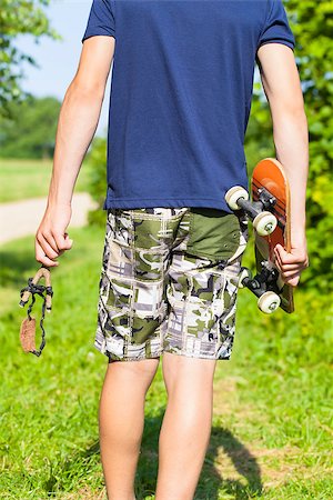 estilingue - Boy with a slingshot and skateboard on rural road Foto de stock - Royalty-Free Super Valor e Assinatura, Número: 400-07087073