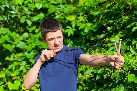 Boy with a slingshot near the bush Foto de stock - Royalty-Free Super Valor e Assinatura, Número: 400-07087080
