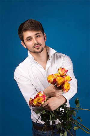 simsearch:400-05294518,k - Man with bouquet of red roses. On blue background. Fotografie stock - Microstock e Abbonamento, Codice: 400-07087870