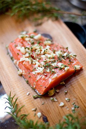 Wild Alaskan salmon fillet on a cedar plank that is ready to be grilled.  It's seasoned with garlic, rosemary, salt and pepper. Photographie de stock - Aubaine LD & Abonnement, Code: 400-07096532