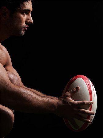 one caucasian sexy naked  man portrait holding rugby ball on studio black background Stock Photo - Budget Royalty-Free & Subscription, Code: 400-07097861