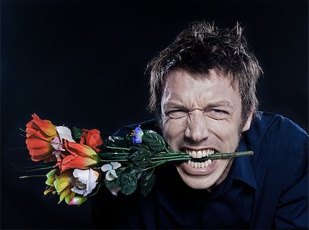 simsearch:400-07097695,k - studio portrait on black background of a funny expressive caucasian man offering flowers anger Stock Photo - Budget Royalty-Free & Subscription, Code: 400-07098755