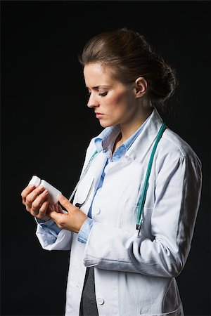 simsearch:400-07099832,k - Doctor woman looking on medicine bottle on black background Stock Photo - Budget Royalty-Free & Subscription, Code: 400-07099879