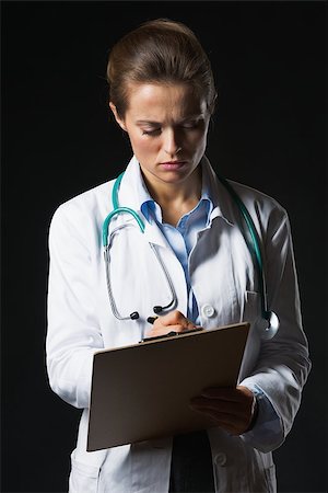 simsearch:400-07099823,k - Serious doctor woman writing in clipboard on black background Stock Photo - Budget Royalty-Free & Subscription, Code: 400-07099880