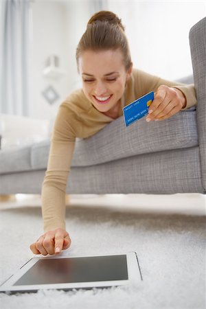 Happy young woman with credit card using tablet pc while laying on sofa Stock Photo - Budget Royalty-Free & Subscription, Code: 400-07104786