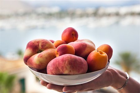simsearch:400-07667203,k - Assorted colorful fresh summer fruits - apricots and donut peaches in the bowl on the hand Stock Photo - Budget Royalty-Free & Subscription, Code: 400-07106490