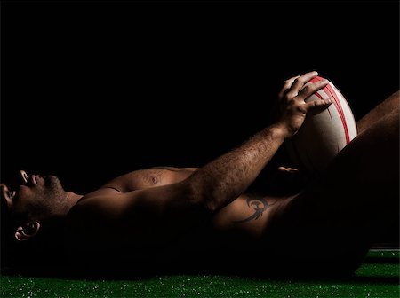 one caucasian sexy naked  man portrait holding rugby ball on studio black background Stock Photo - Budget Royalty-Free & Subscription, Code: 400-07100716