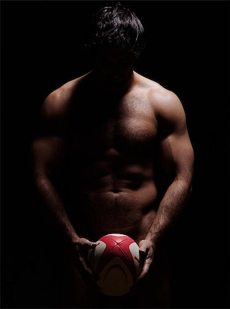 one caucasian sexy naked  man portrait holding rugby ball on studio black background Stock Photo - Budget Royalty-Free & Subscription, Code: 400-07101595