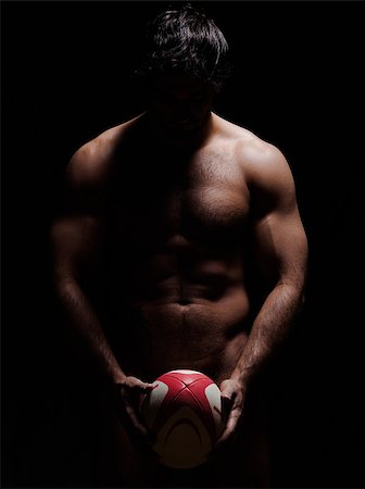 one caucasian sexy naked  man portrait holding rugby ball on studio black background Stock Photo - Budget Royalty-Free & Subscription, Code: 400-07103125