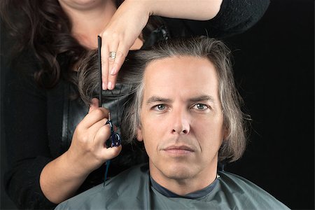 Close-up of a serious man looking to camera while his long hair is cut off for a cancer fundraiser. Photographie de stock - Aubaine LD & Abonnement, Code: 400-07115680