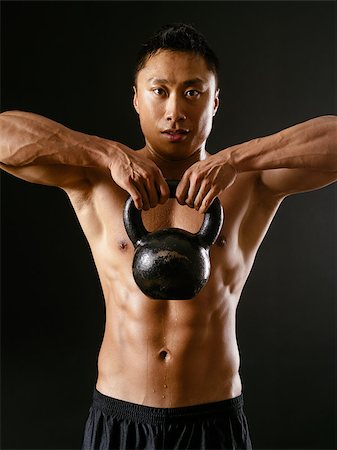 Photo of an Asian male exercising with a kettle bell over dark background. Stock Photo - Budget Royalty-Free & Subscription, Code: 400-07124054