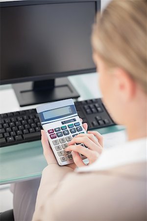 Over shoulder view of businesswoman using calculator in bright office Stock Photo - Budget Royalty-Free & Subscription, Code: 400-07125857
