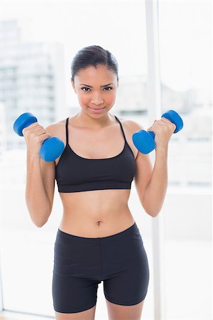 fitness model adult - Dynamic dark haired model in sportswear exercising with dumbbells in bright fitness studio Stock Photo - Budget Royalty-Free & Subscription, Code: 400-07127152