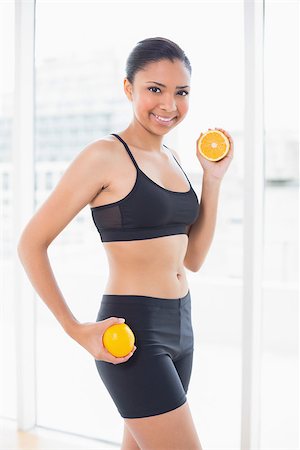 fitness model adult - Dynamic dark haired model in sportswear holding orange halves in bright fitness studio Stock Photo - Budget Royalty-Free & Subscription, Code: 400-07127173