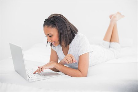 simsearch:400-07127341,k - Content young dark haired model using a laptop in bright bedroom Stock Photo - Budget Royalty-Free & Subscription, Code: 400-07127259