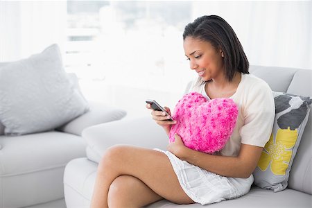 simsearch:400-07127324,k - Pensive young dark haired woman in white clothes using a mobile phone in a living room Photographie de stock - Aubaine LD & Abonnement, Code: 400-07127332