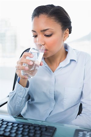 Calm young dark haired businesswoman drinking water in bright office Stock Photo - Budget Royalty-Free & Subscription, Code: 400-07127409
