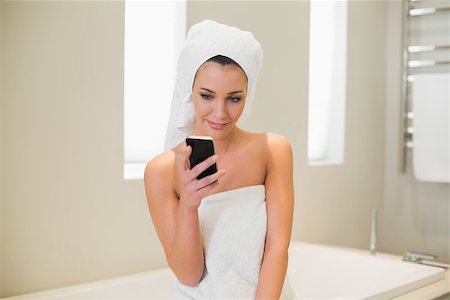 Pleased natural brown haired woman using her mobile phone in a bright bathroom Stock Photo - Budget Royalty-Free & Subscription, Code: 400-07128766