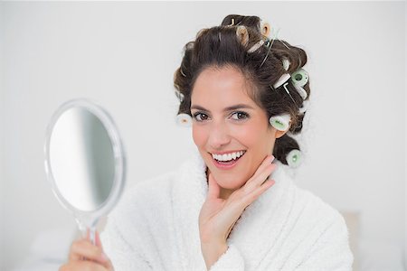 Cheerful natural brunette holding hand mirror in bedroom Photographie de stock - Aubaine LD & Abonnement, Code: 400-07128814