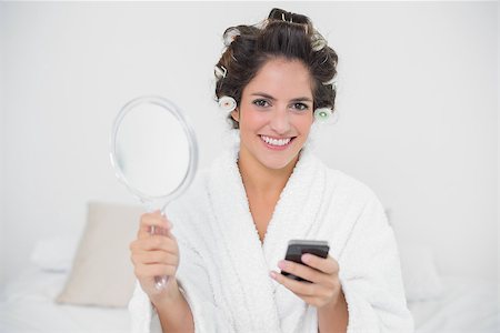 Content natural brunette holding mirror and smartphone in bedroom Stock Photo - Budget Royalty-Free & Subscription, Code: 400-07128824