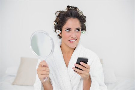 Pensive natural brunette holding mirror and smartphone in bedroom Photographie de stock - Aubaine LD & Abonnement, Code: 400-07128826