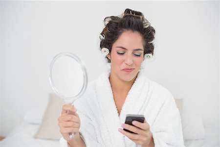 Smiling natural brunette holding mirror and smartphone in bedroom Stock Photo - Budget Royalty-Free & Subscription, Code: 400-07128823