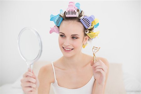 Beautiful natural brown haired woman in hair curlers looking herself in a mirror in bright bedroom Stock Photo - Budget Royalty-Free & Subscription, Code: 400-07129752