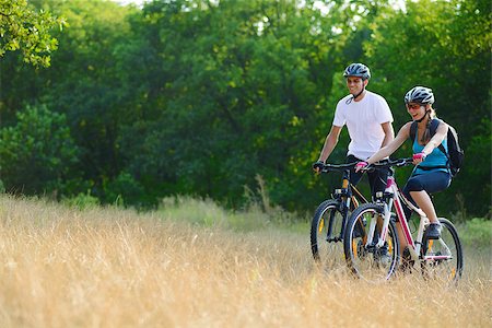 Young Happy Couple Riding Mountain Bikes Outdoor. Healthy Lifestyle Concept Foto de stock - Royalty-Free Super Valor e Assinatura, Número: 400-07123235