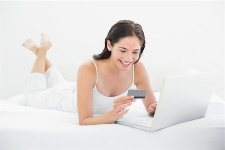 simsearch:6109-06194946,k - Casual young woman doing online shopping through laptop and credit card in bed Fotografie stock - Microstock e Abbonamento, Codice: 400-07134010