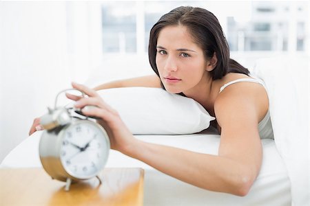 simsearch:614-02613098,k - Portrait of a young woman in bed extending hand to alarm clock at home Stockbilder - Microstock & Abonnement, Bildnummer: 400-07134036