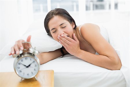 simsearch:614-02613098,k - Young woman yawning while extending hand to alarm clock in bed Stockbilder - Microstock & Abonnement, Bildnummer: 400-07134040