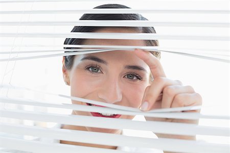 Close up portrait of a smiling young business woman peeking through blinds Stock Photo - Budget Royalty-Free & Subscription, Code: 400-07134334