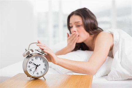 simsearch:614-02613098,k - Young woman yawning while extending hand to alarm clock in bed Stockbilder - Microstock & Abonnement, Bildnummer: 400-07134735