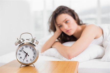 Sleepy young woman looking at alarm clock on bedside table in the bedroom Stock Photo - Budget Royalty-Free & Subscription, Code: 400-07134739
