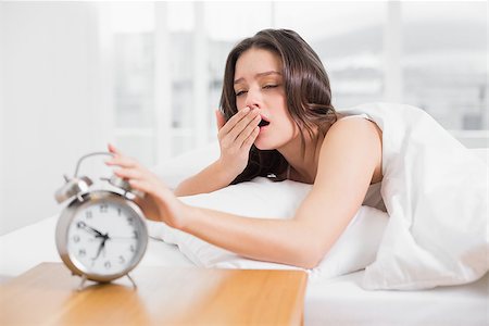 simsearch:614-02613098,k - Young woman yawning while extending hand to alarm clock in bed Stockbilder - Microstock & Abonnement, Bildnummer: 400-07134732