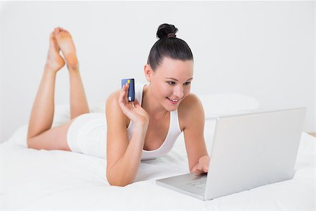 simsearch:6109-06194946,k - Casual young woman doing online shopping through laptop and credit card in bed Fotografie stock - Microstock e Abbonamento, Codice: 400-07135194