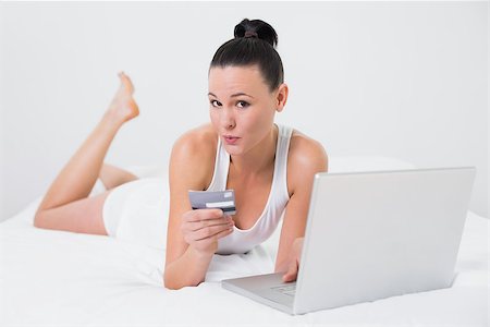 simsearch:6109-06194946,k - Portrait of a casual young woman doing online shopping through laptop and credit card in bed Fotografie stock - Microstock e Abbonamento, Codice: 400-07135197