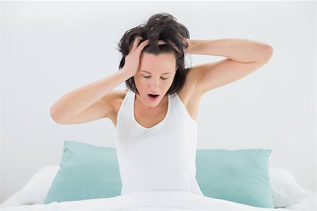 simsearch:614-06813544,k - Sleepy young woman yawning while stretching her arms in bed at home Stockbilder - Microstock & Abonnement, Bildnummer: 400-07135257