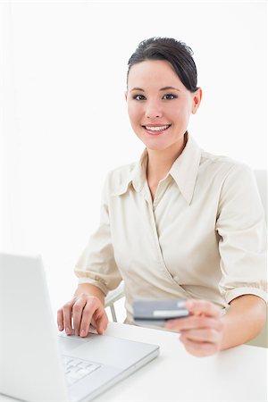 simsearch:400-07268814,k - Portrait of a smiling young businesswoman doing online shopping through laptop and credit card Foto de stock - Royalty-Free Super Valor e Assinatura, Número: 400-07135455