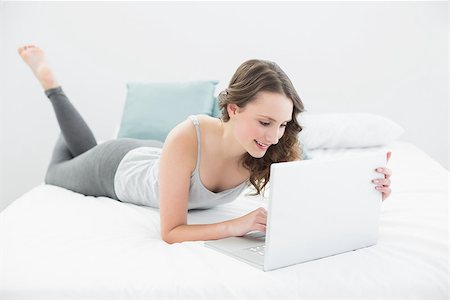 Smiling casual young brunette using laptop in bed at home Stock Photo - Budget Royalty-Free & Subscription, Code: 400-07136414