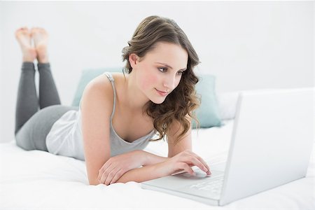 Relaxed casual young brunette using laptop in bed at home Stock Photo - Budget Royalty-Free & Subscription, Code: 400-07136423