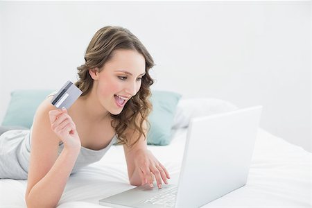 simsearch:400-07268814,k - Casual young woman doing online shopping through laptop and credit card in bed Foto de stock - Royalty-Free Super Valor e Assinatura, Número: 400-07136436