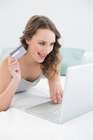 simsearch:400-07268814,k - Casual young woman doing online shopping through laptop and credit card in bed Foto de stock - Royalty-Free Super Valor e Assinatura, Número: 400-07136438