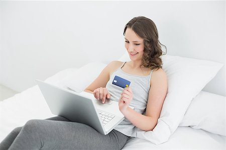 simsearch:400-07268814,k - Casual young woman doing online shopping through laptop and credit card in bed Foto de stock - Royalty-Free Super Valor e Assinatura, Número: 400-07136439