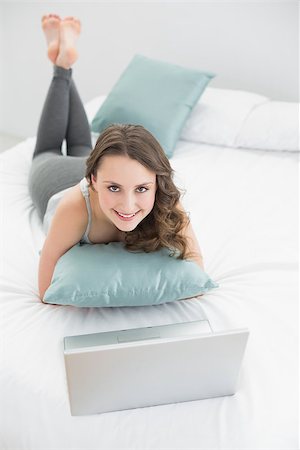 High angle portrait of a casual young brunette with laptop lying in bed at home Stock Photo - Budget Royalty-Free & Subscription, Code: 400-07136430