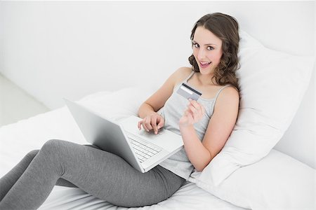 simsearch:400-07268814,k - Casual young woman doing online shopping through laptop and credit card in bed Foto de stock - Royalty-Free Super Valor e Assinatura, Número: 400-07136442